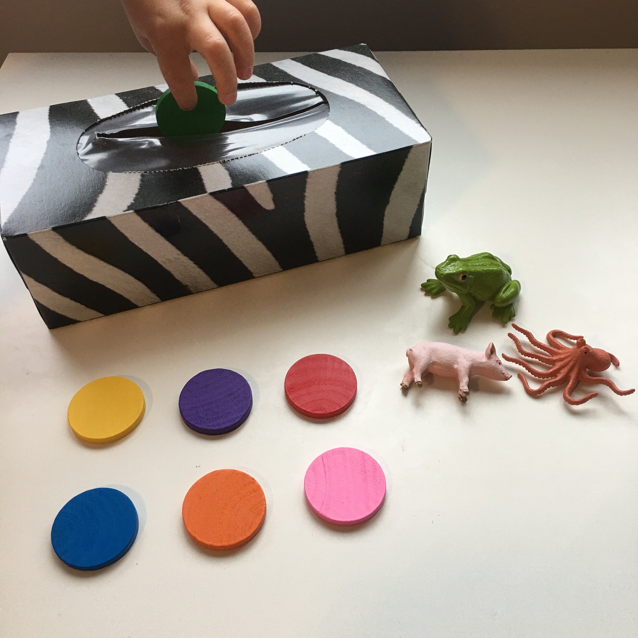 “What’s inside my box game?” Show your child a few objects by presenting them like in this picture. Have them cover their eyes and place one object in the box. Can they recognize which object is missing?