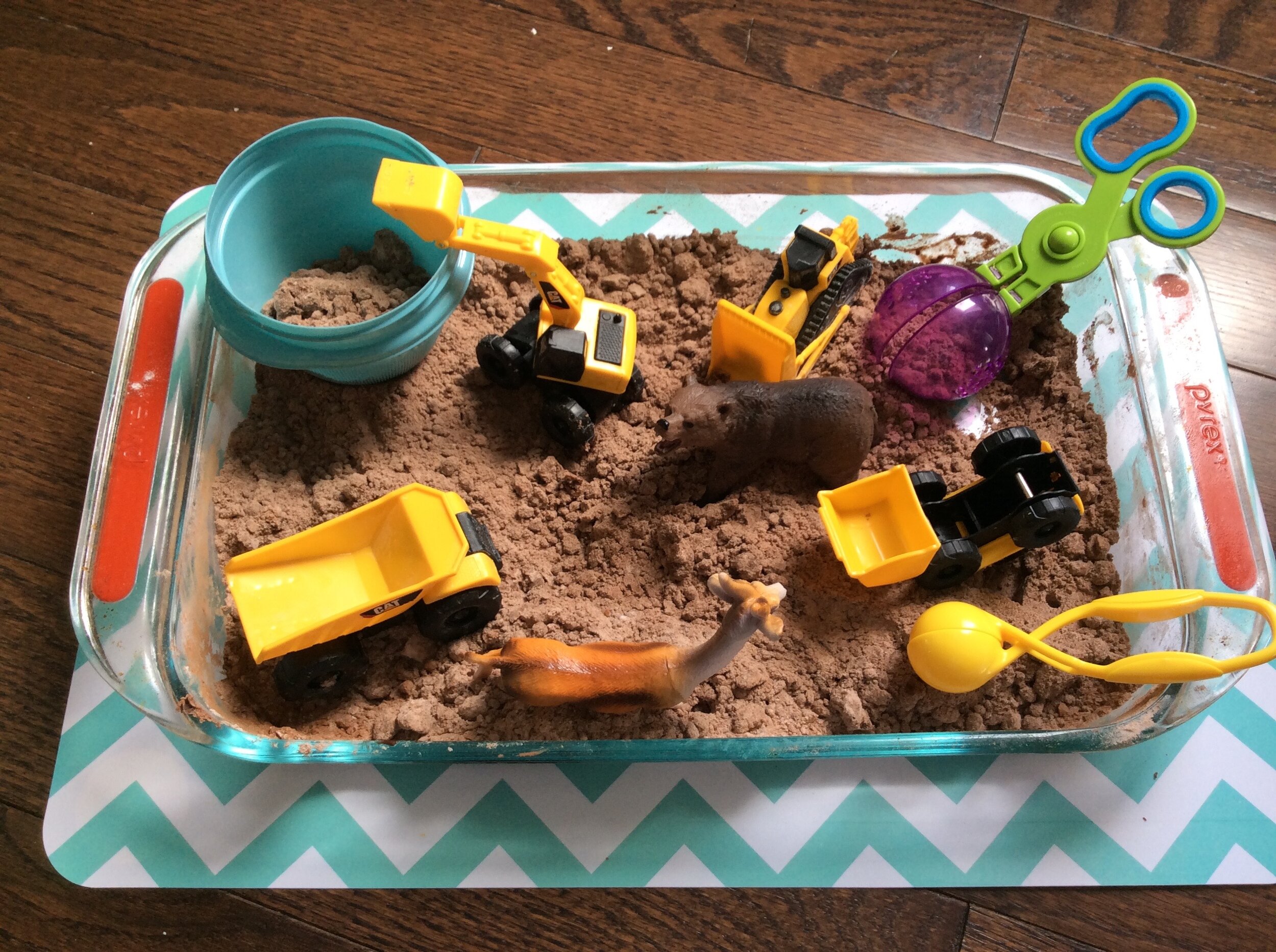 Anything could be used as a sensory bin, here, I used a baking dish. I added some flour with a few spoonfuls of cocoa power to make it look like dirt and added trucks!