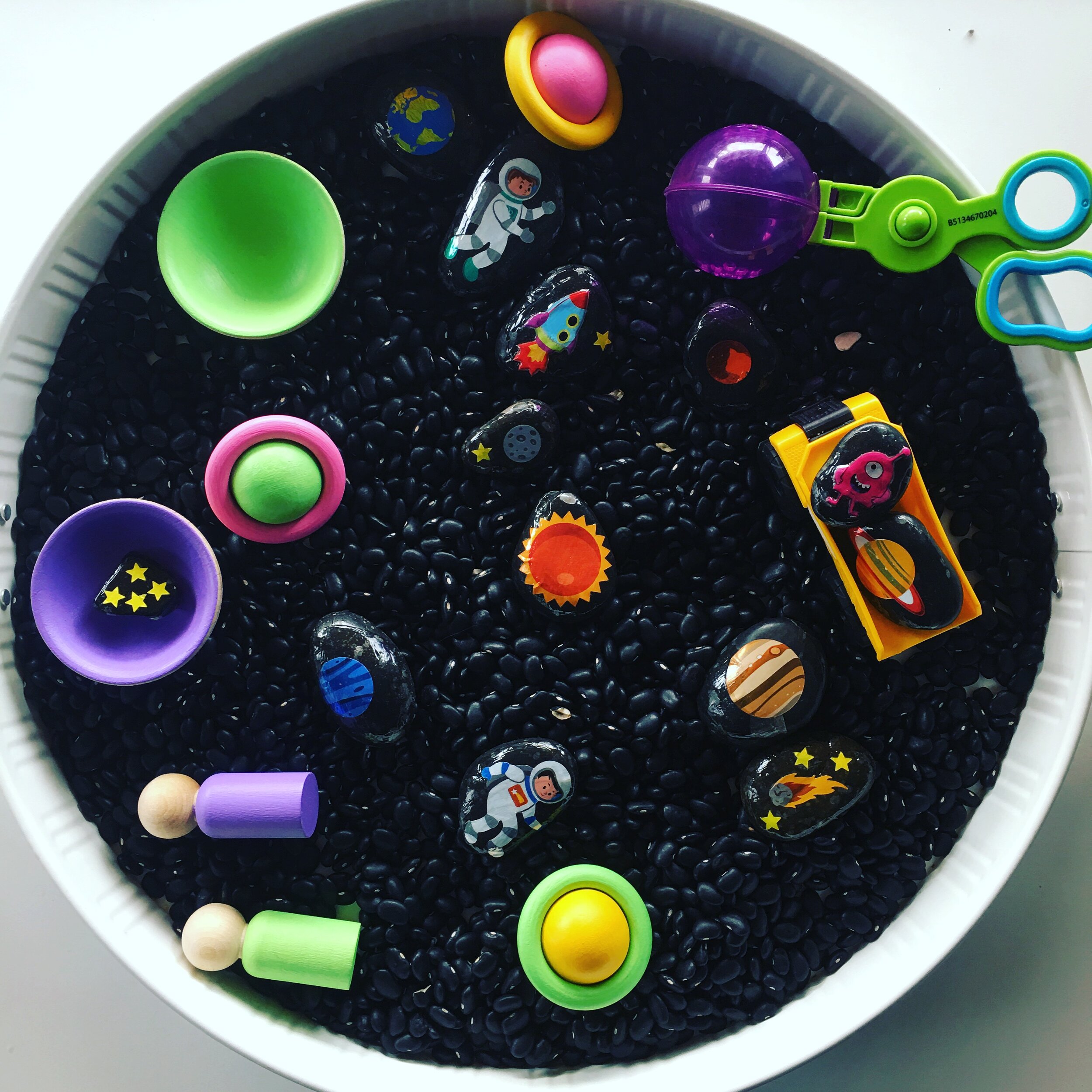 I used black beans along with some trucks, bowls and loose parts from @chickadeeswoodentoys, motor tools from Learning Resources and added outer space stickers to some black rocks!