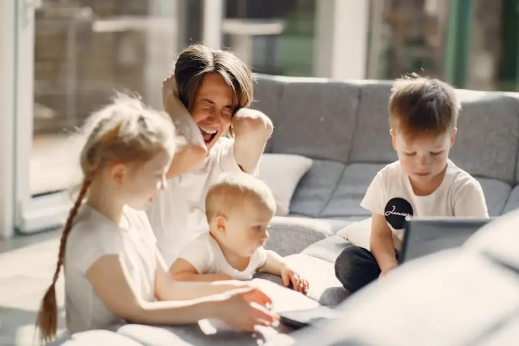 Parent showing signs of stress while her children play on screens.