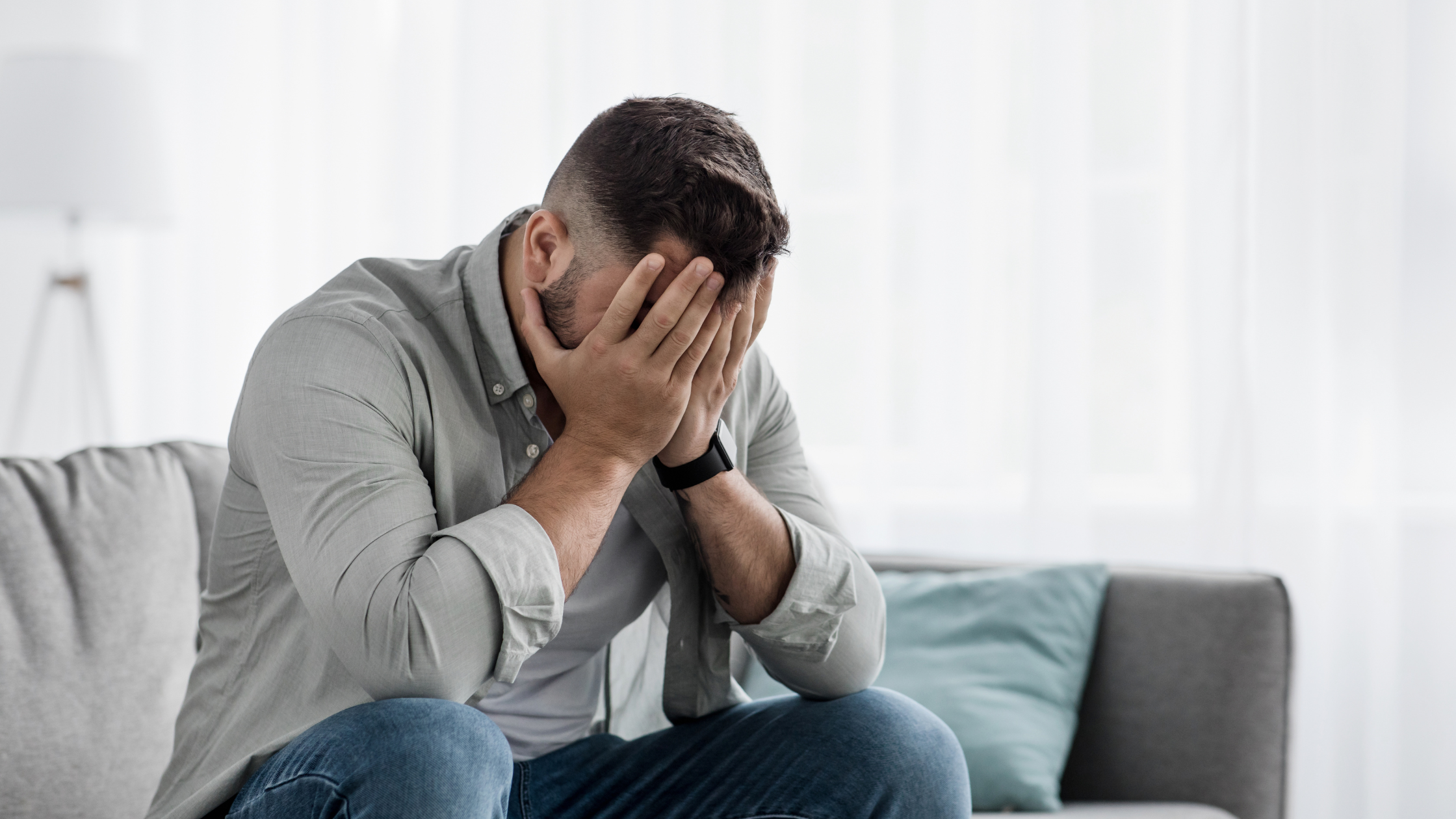 a father sits on a sofa with this head in his hands