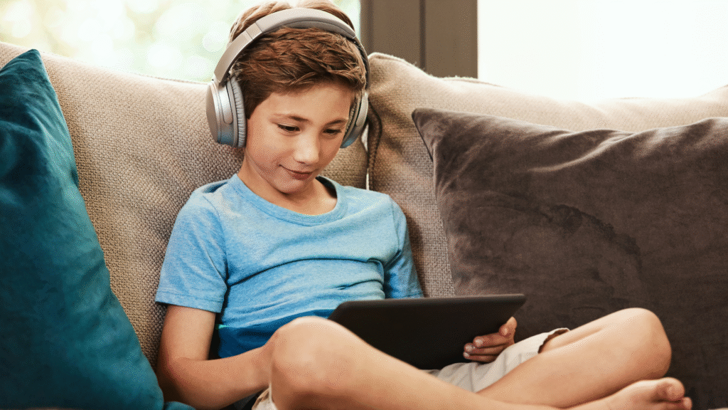 child sitting on couch with headphones and an ipad using social media